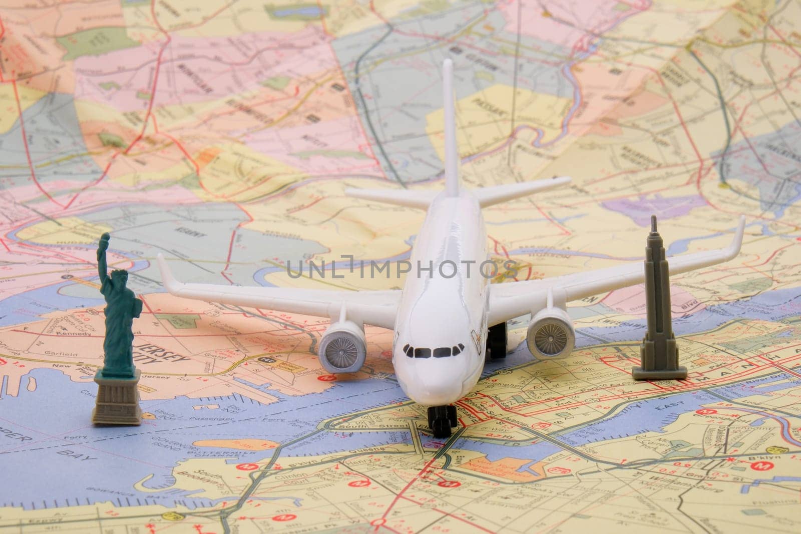 Close up detail of a miniature passenger plane on a colorful map of New York with a toy Empire State building, Statue of Liberty . High quality photo