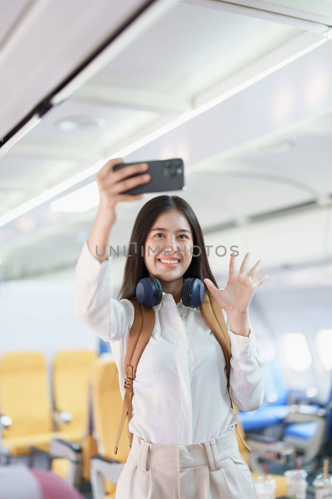 Asian business woman passenger sitting on business class luxury plane while working using smart phone mobile talking or video conference and travel concept.