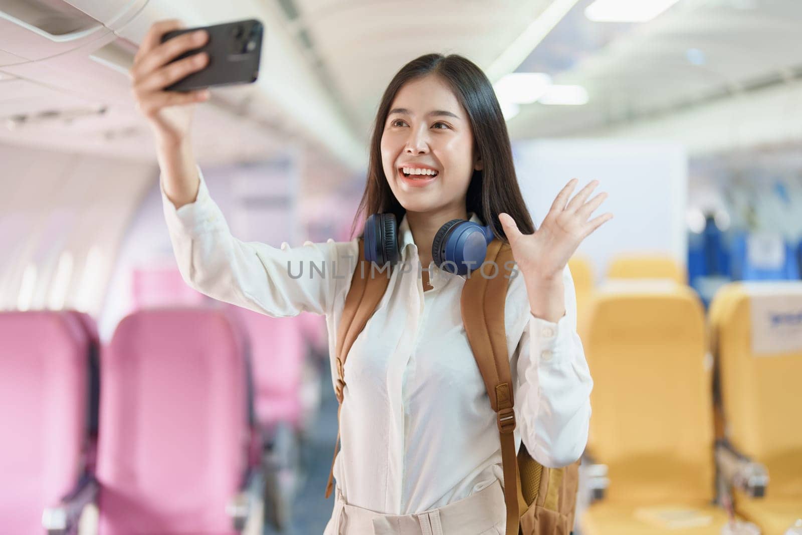 Asian business woman passenger sitting on business class luxury plane while working using smart phone mobile talking or video conference and travel concept.