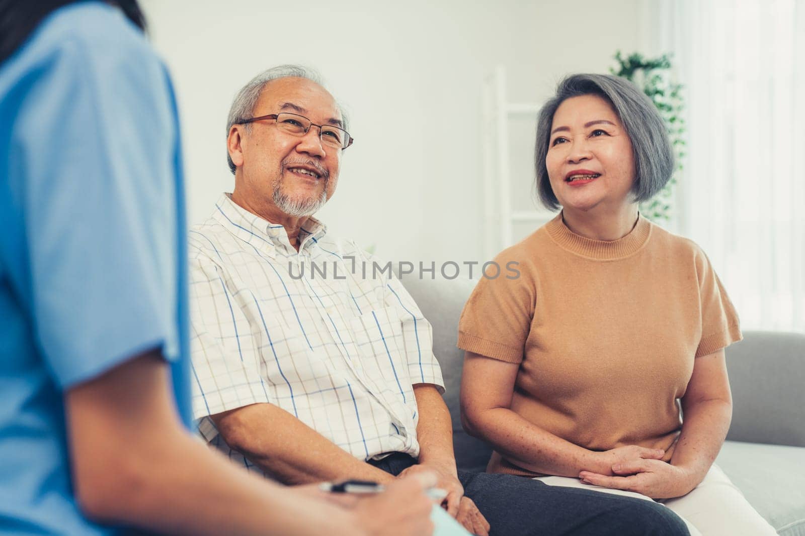 Female doctor visiting a contented elderly couple at their home. Health care, senior health support staff.