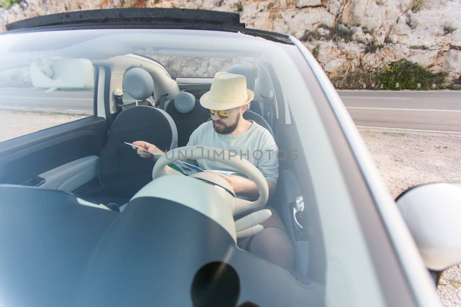 Hipster man looking on location navigation map in car, tourist traveler driving and hold in male hands europe cartography, view and plan tourist way road, trip in transportation cabriolet