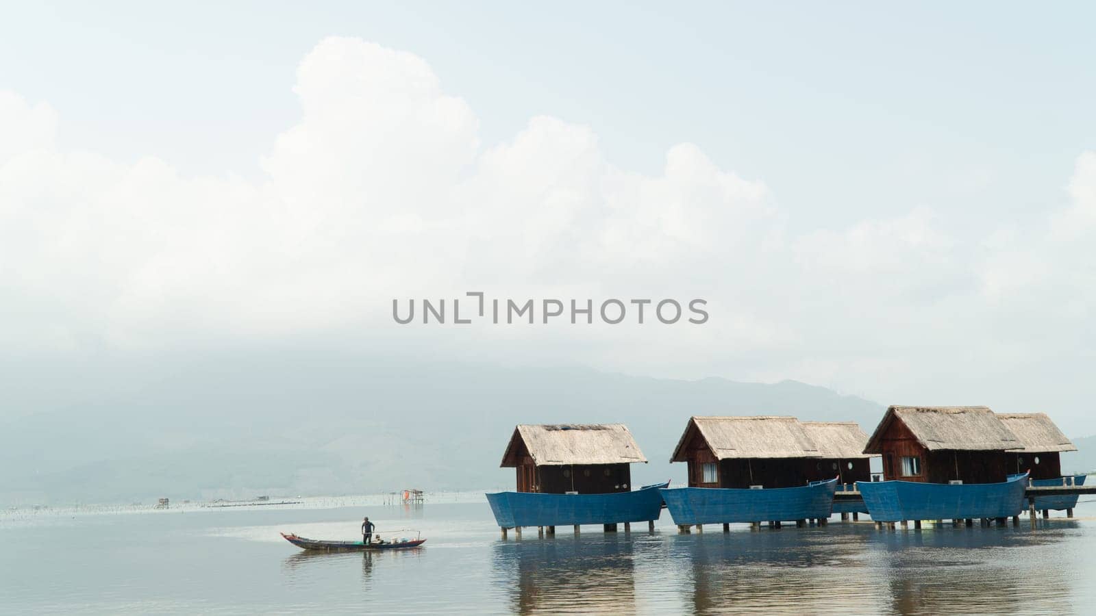 A fisherman in a boat sails away from the bungalow. High quality photo