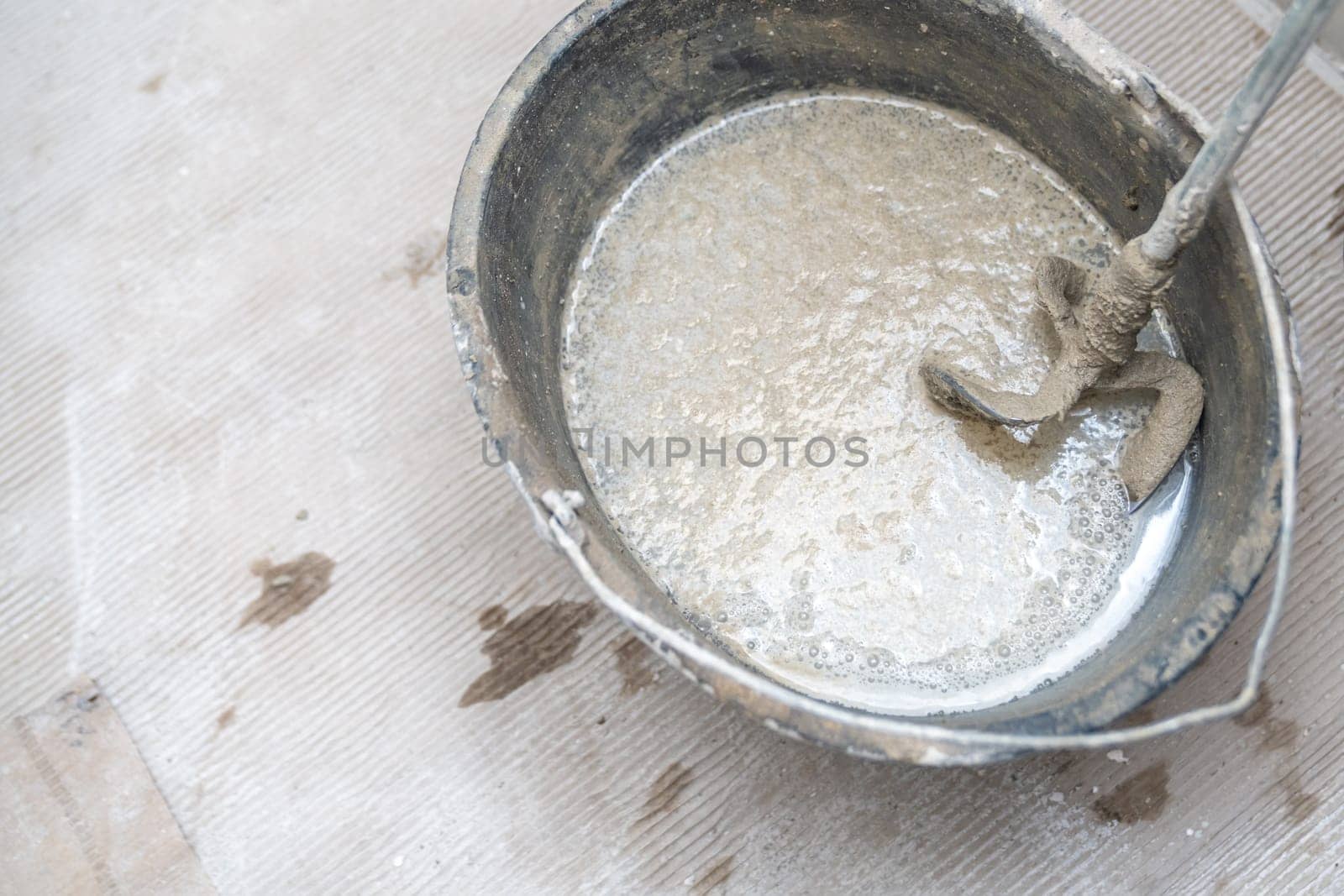 manual mixing of cement with the help of an electric mixer, cement in a bucket on a construction site. High quality photo