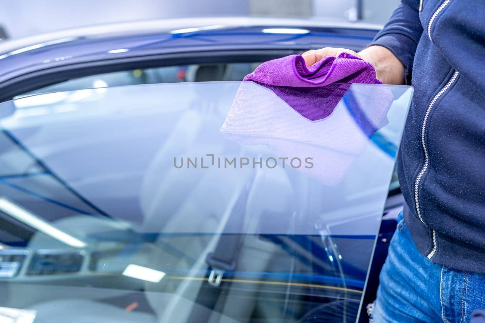 manual cleaning of car windows with a microfiber towel in the garage. High quality photo