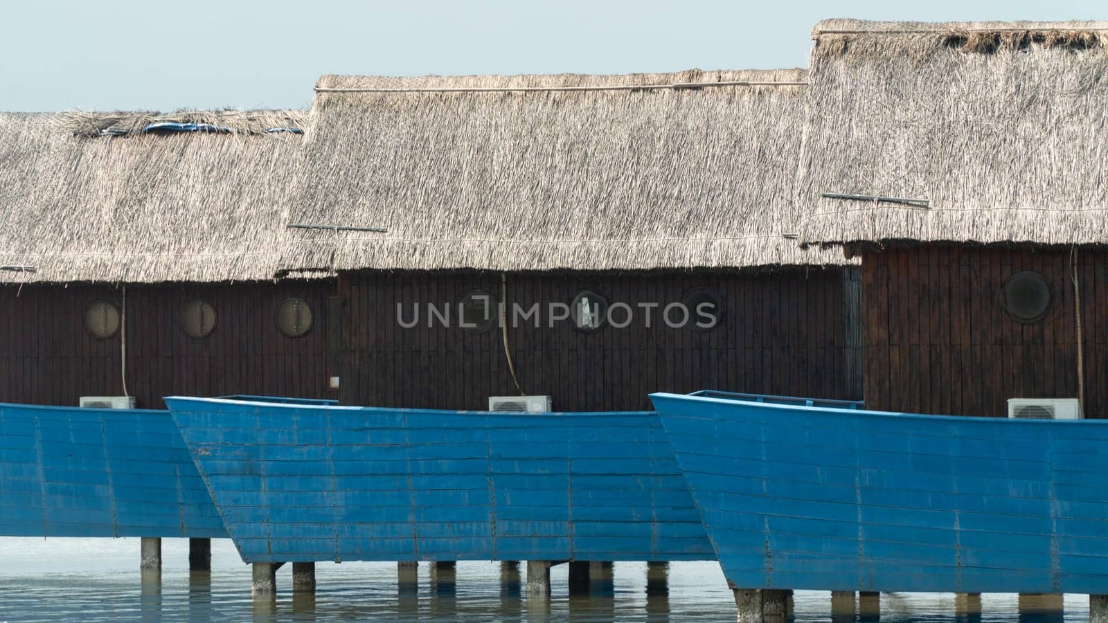 Blue fishing bungalows on stilts in the water by voktybre
