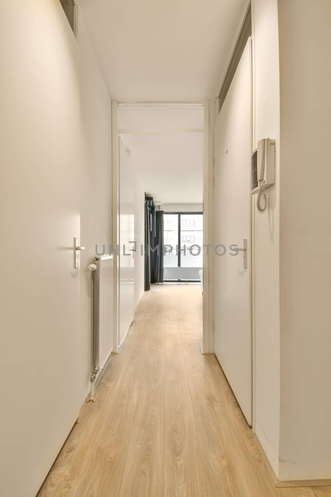 a hallway with white walls and wood floors and a by casamedia