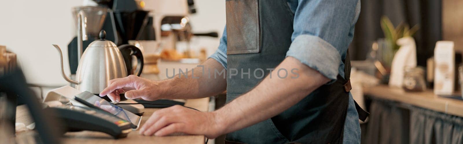 Close up of barista uses a digital tablet to takes order from clients at coffeehouse