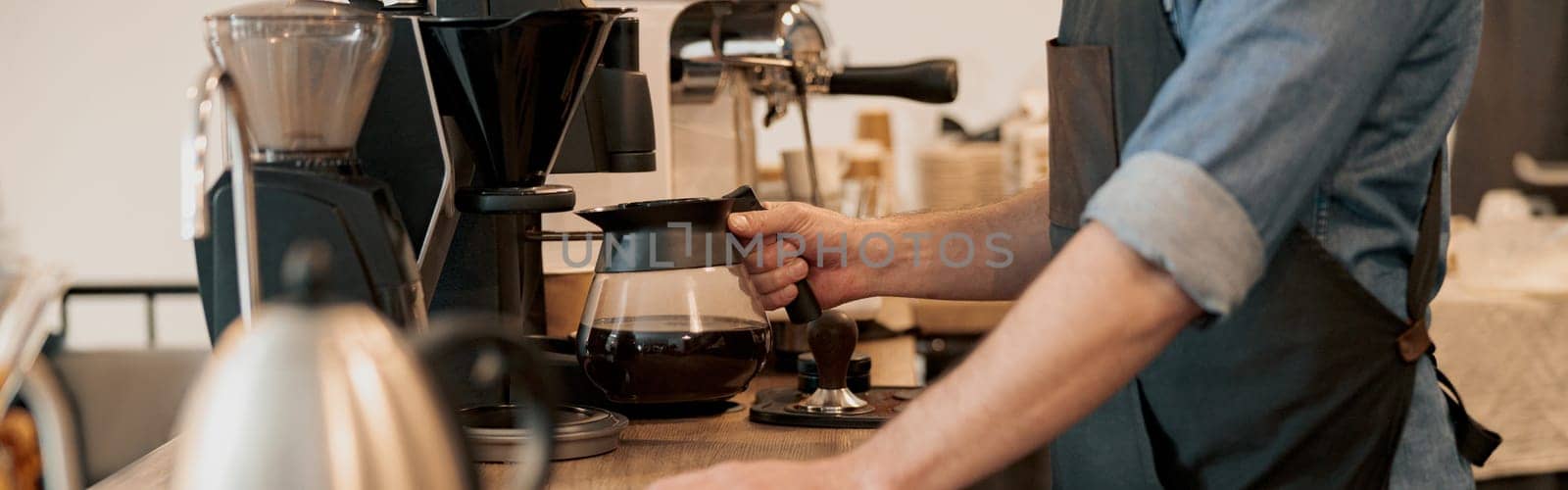 Close up of Male barista holding glass mug standing behind the counter