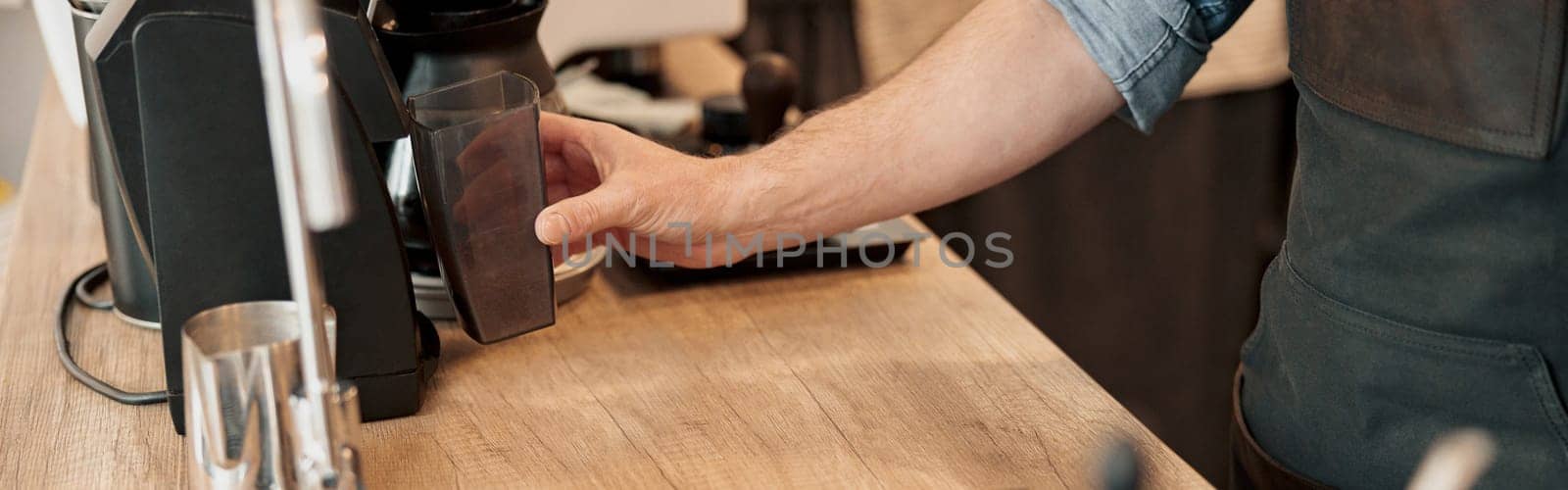 Close up of barista hand installs a container with coffee beans in the coffee machine