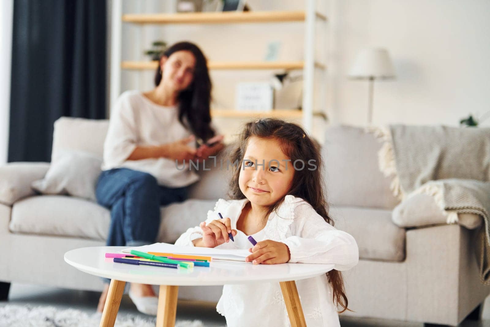 Girls is painting. Mother and her daughter spending time together at home.