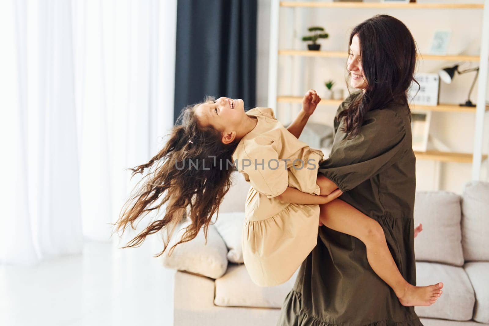 Girl is on the hands of woman. Mother and her daughter spending time together at home.