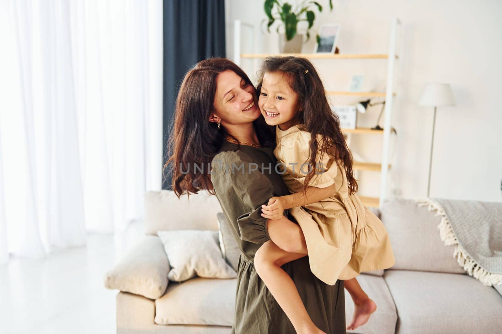 Girl is on the hands of woman. Mother and her daughter spending time together at home.