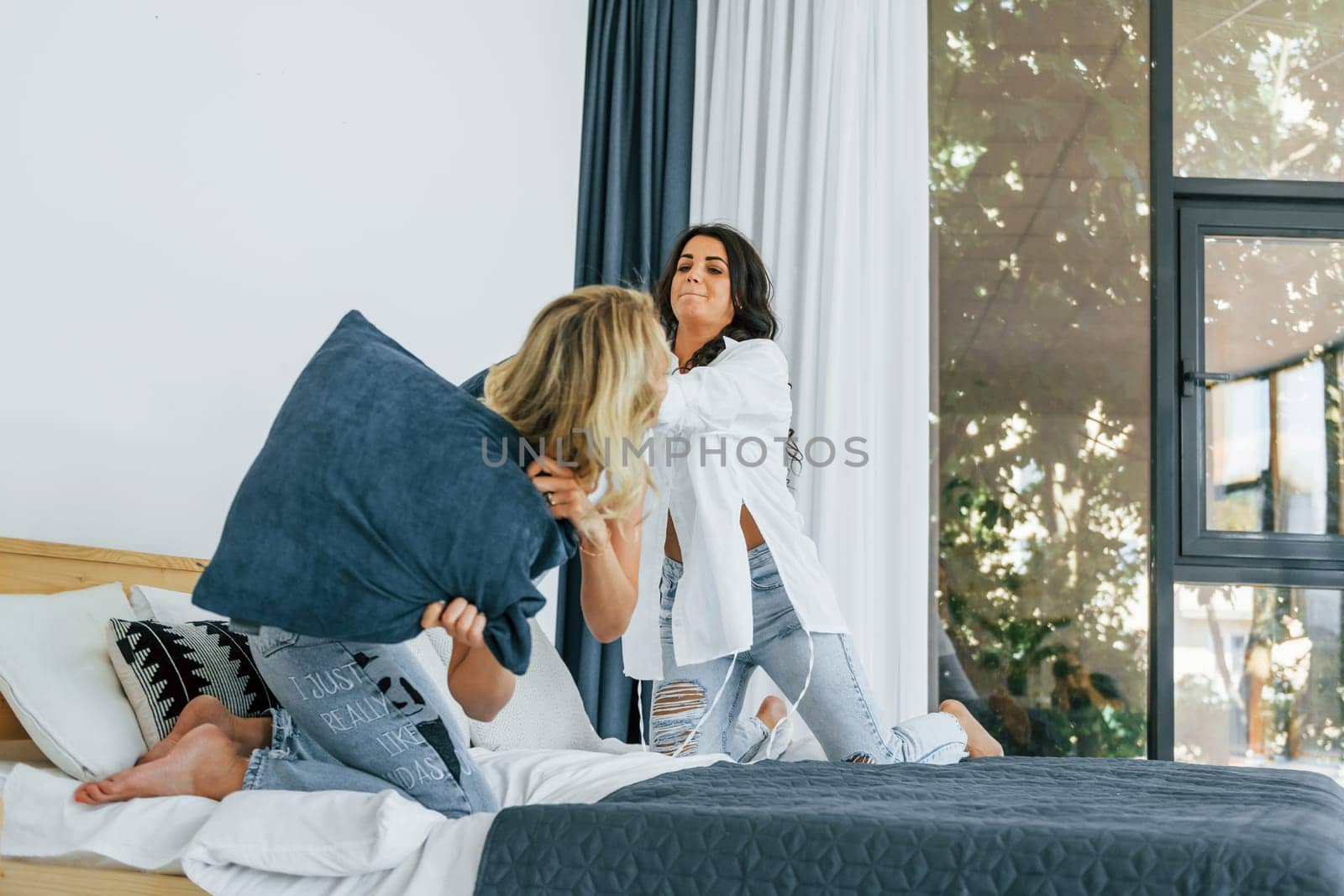 Playing pillow fight. Two women is together at home.