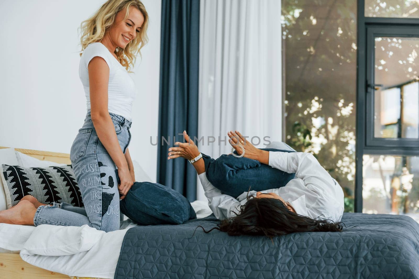 Playing pillow fight. Two women is together at home.