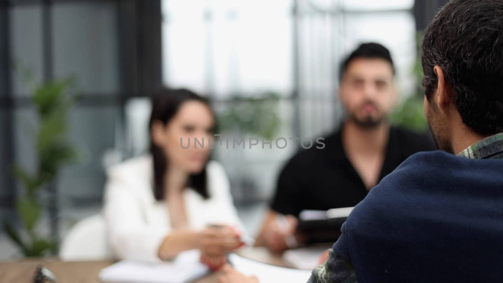 Sits by the table with laptops. Young business people in formal clothes working in the office