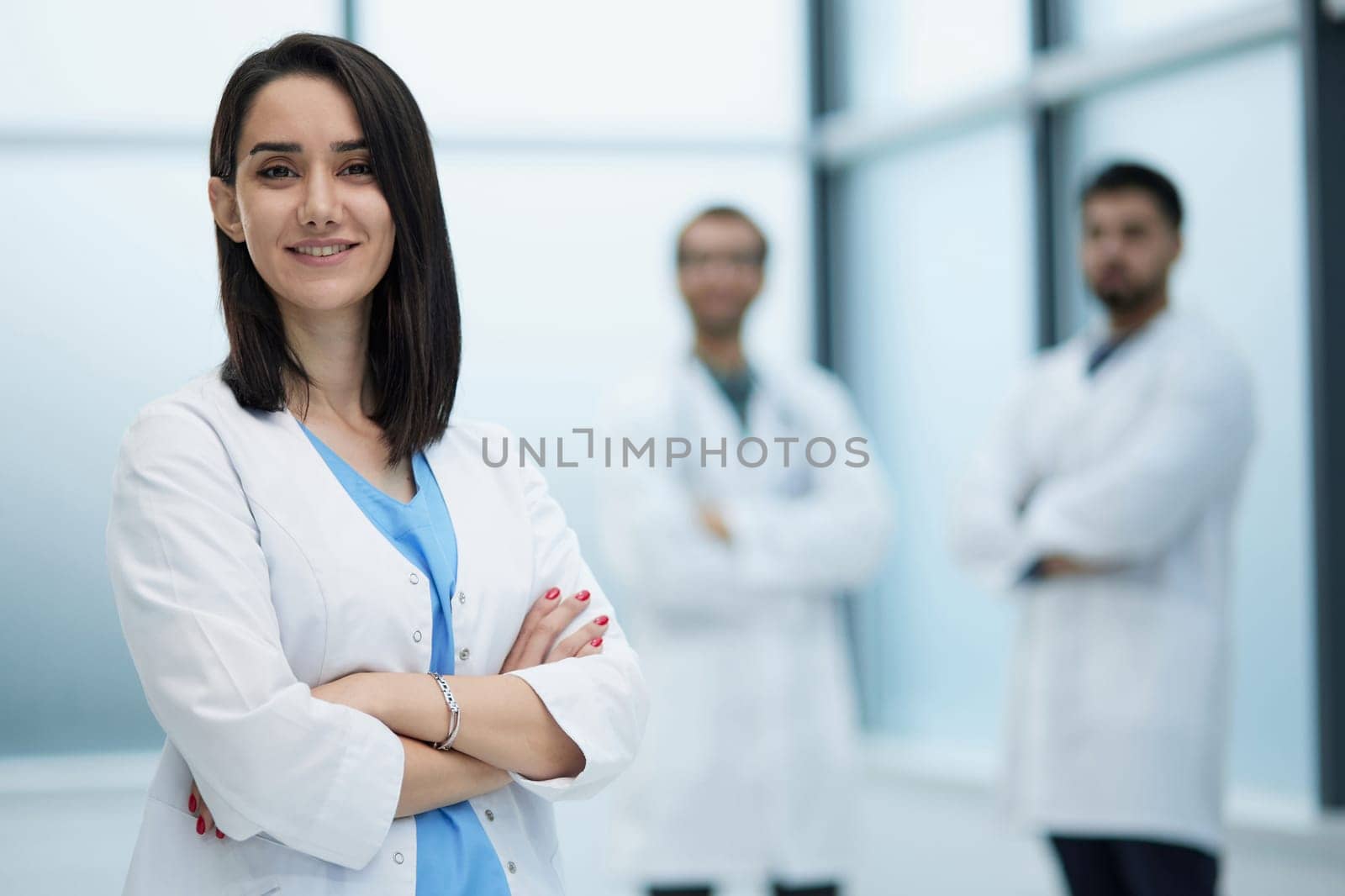 Smiling female doctor in lab coat with arms crossed against by Prosto