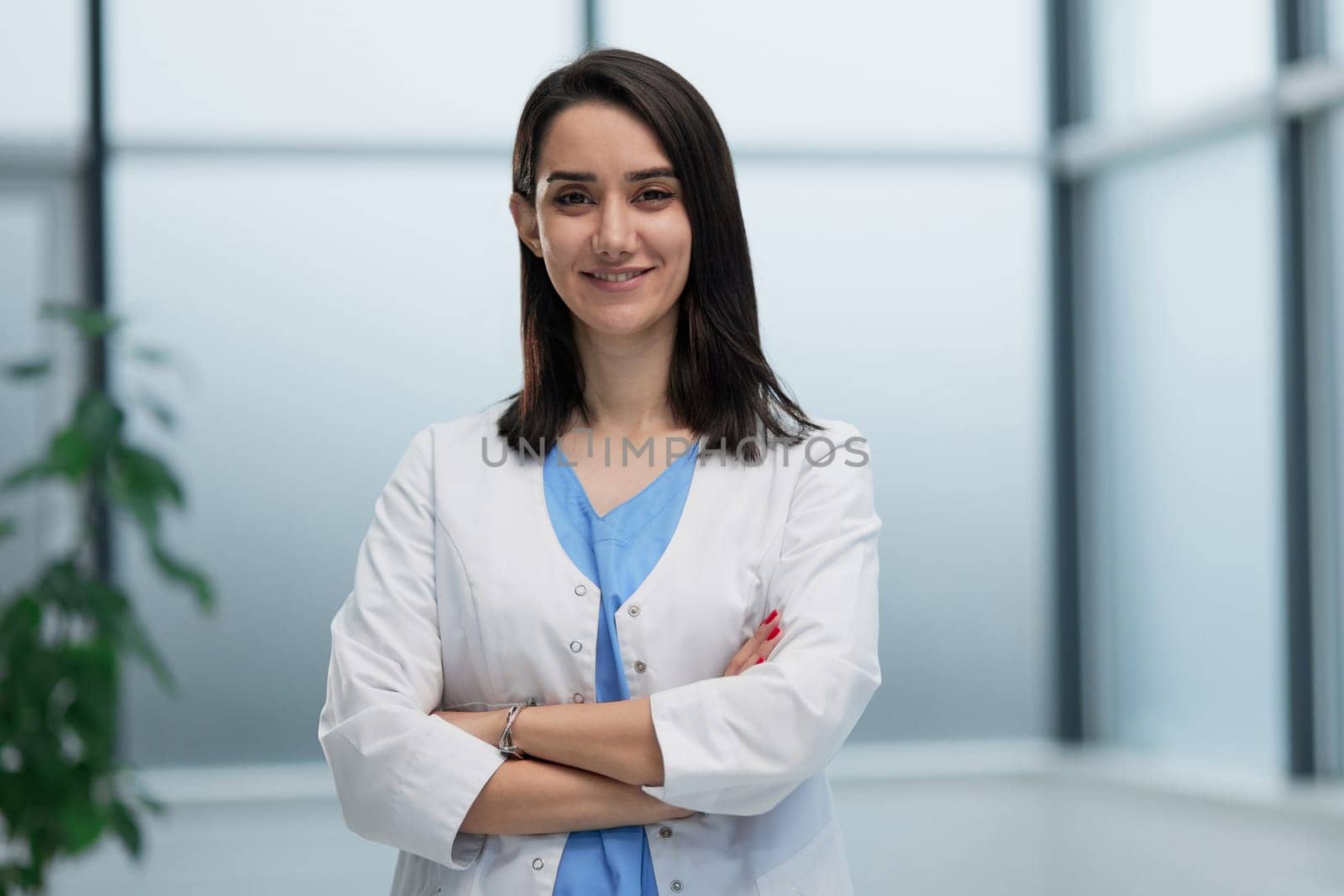 Confident female doctor posing in her office at camera
