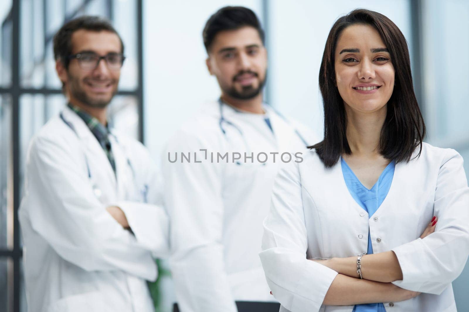 Attractive female doctor in front of the medical staff in the hospital stands with her arms crossed