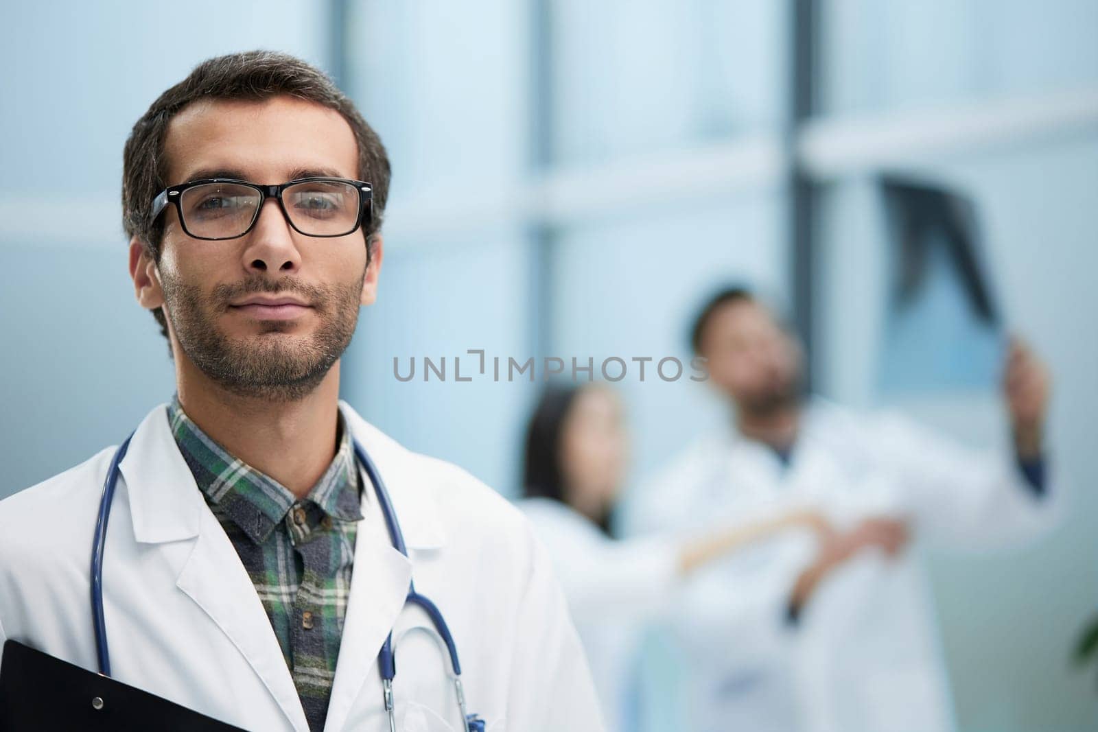 Confident doctor posing with, he is smiling at camera
