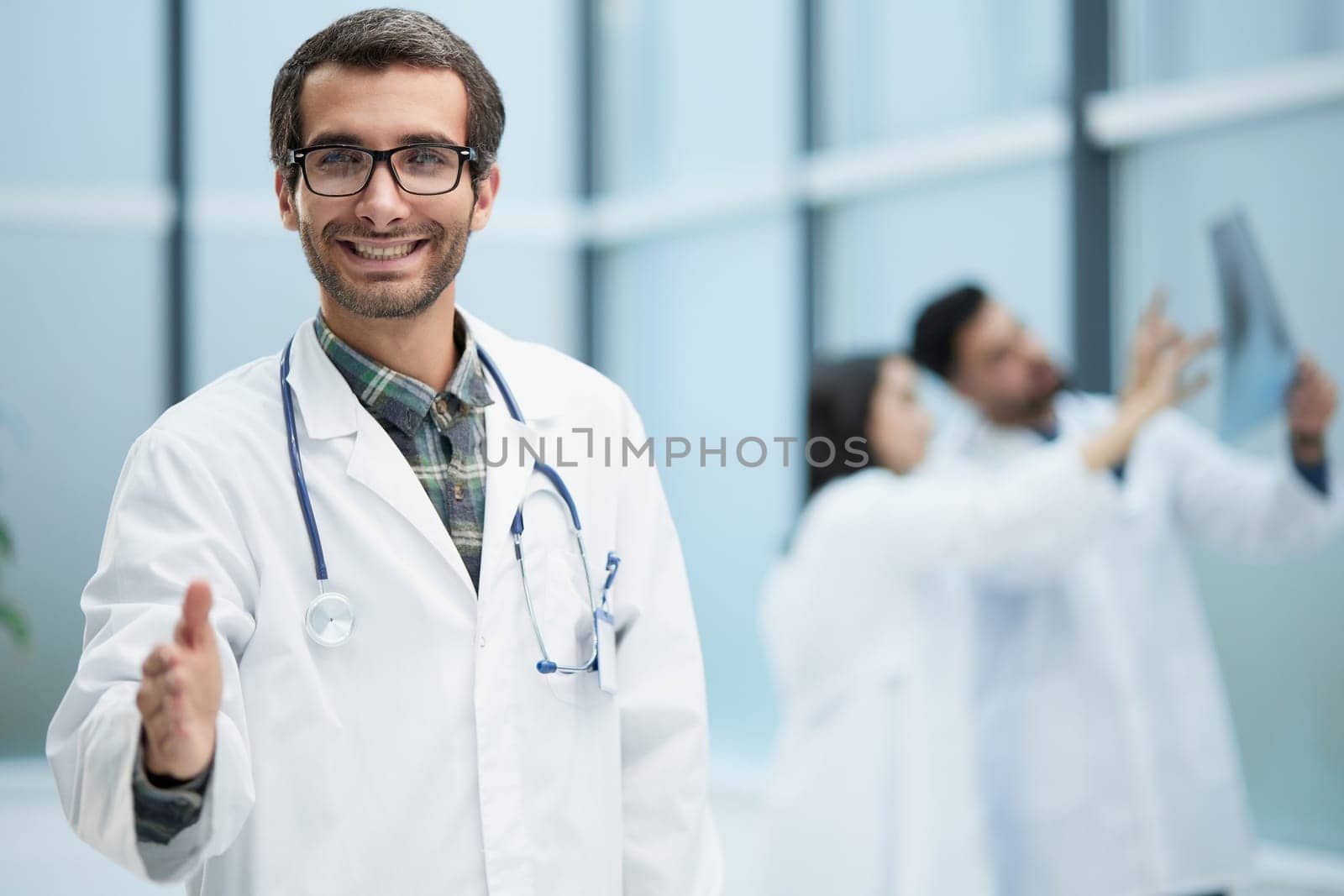 image of a doctor extending his hand in greeting against the background of his colleagues
