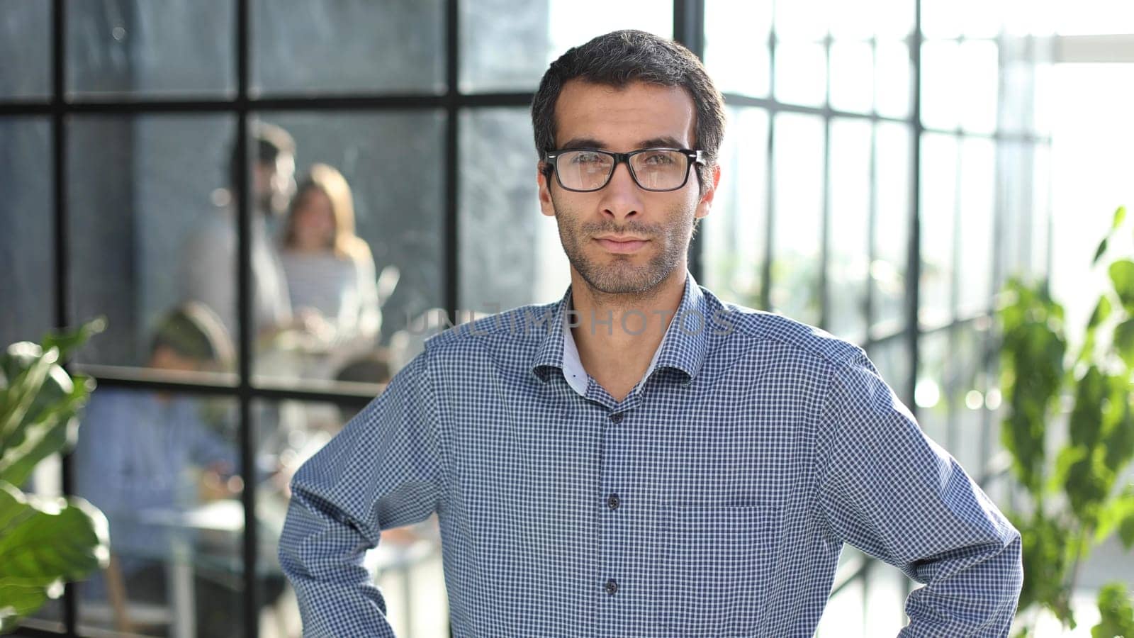 Young businessman in casual clothes stands with his hands on his waist in a modern office