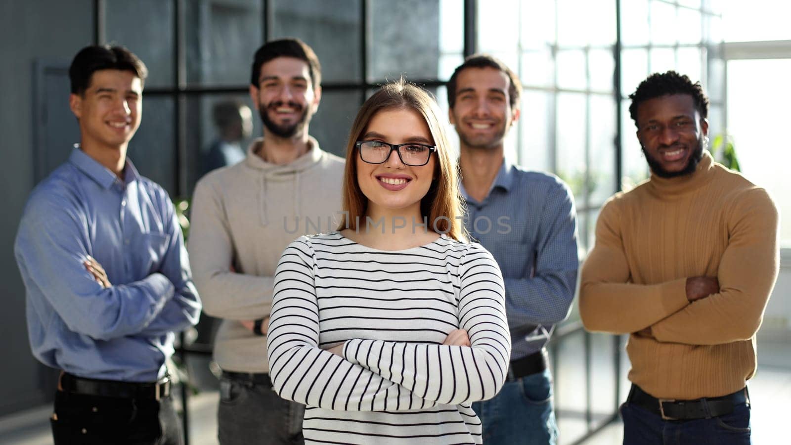 Portrait of business woman and colleagues standing with their arms crossed in the office