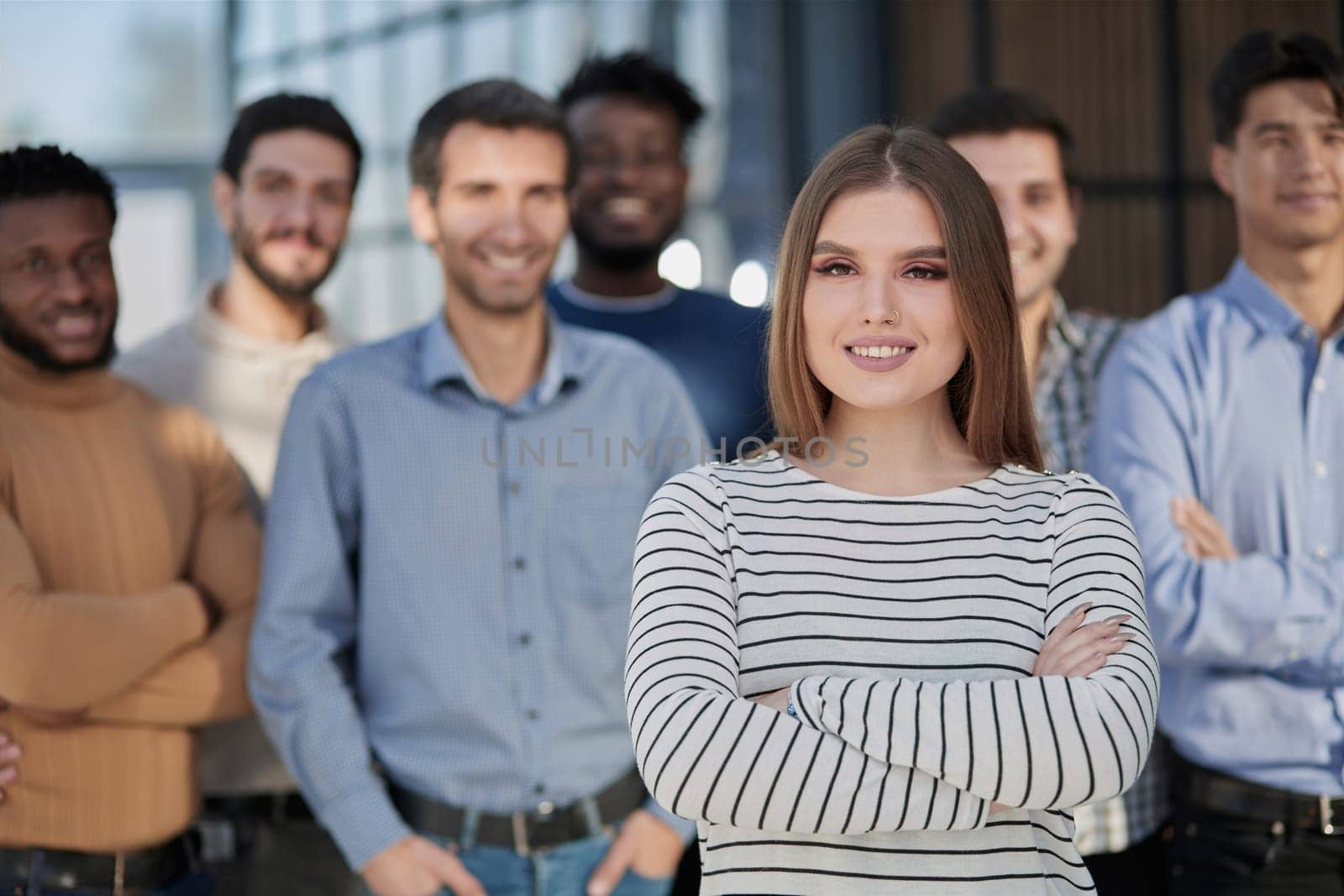 Smiling businesswoman looking at camera together with colleagues in the background