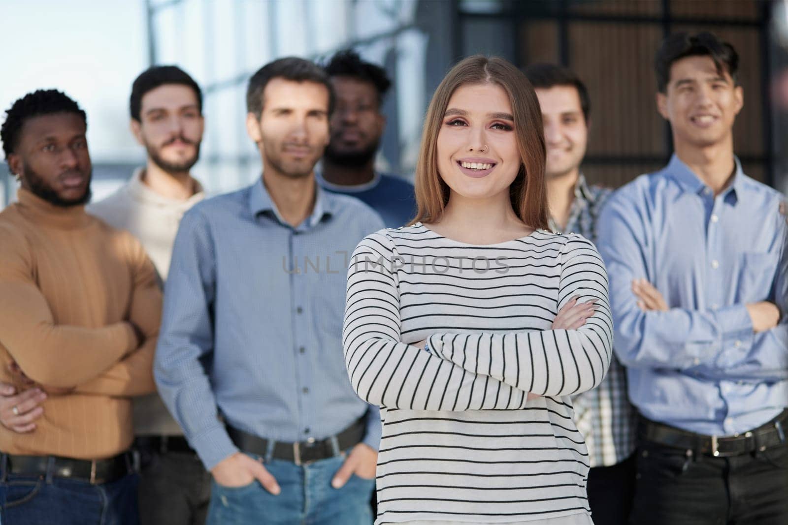 Smiling businesswoman looking at camera together with colleagues in the background