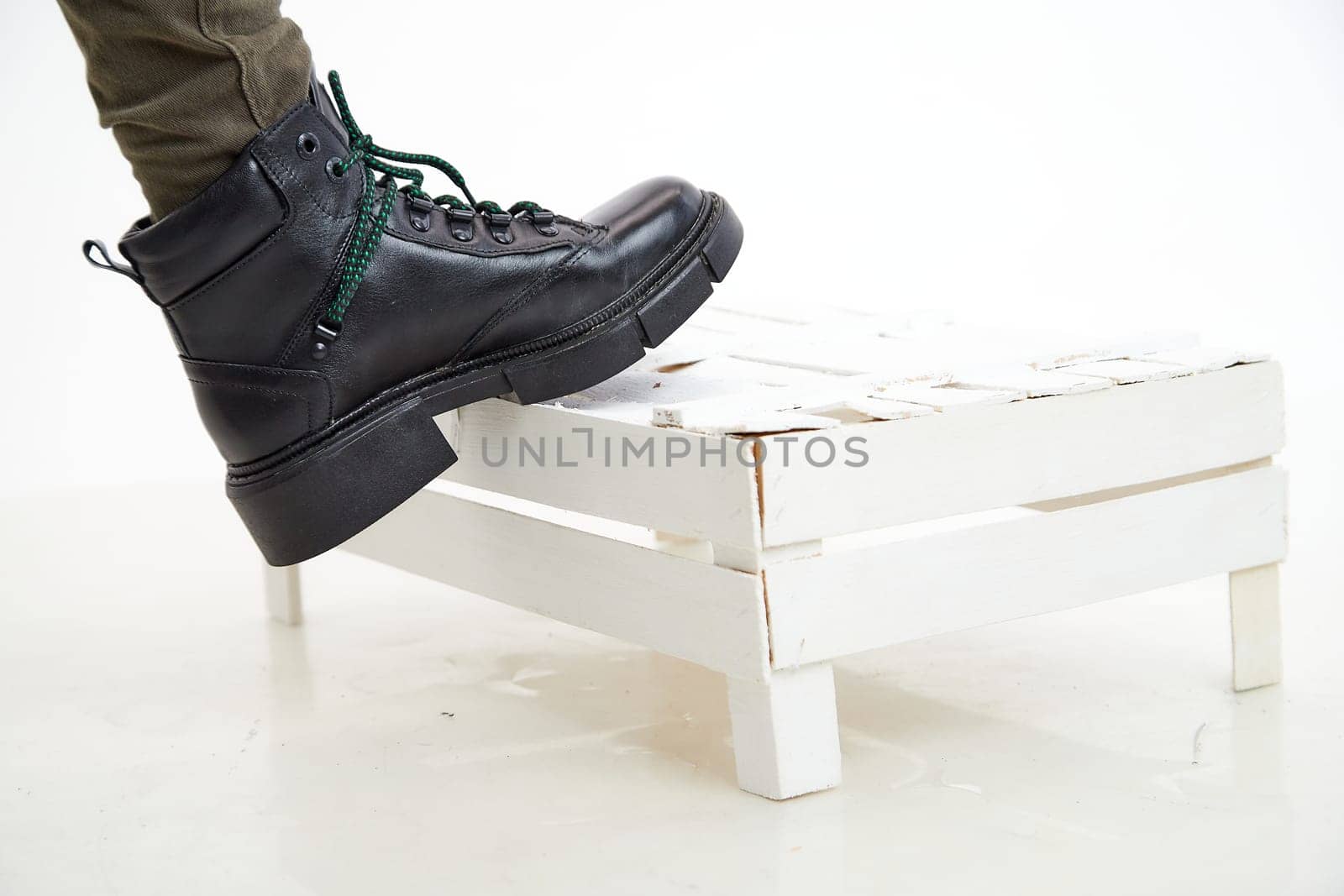 Female winter, autumn or spring black leather shoes on leg of woman in studio on white background. Fashionable modern photography and photoshoot for store, catalog, magazine or online