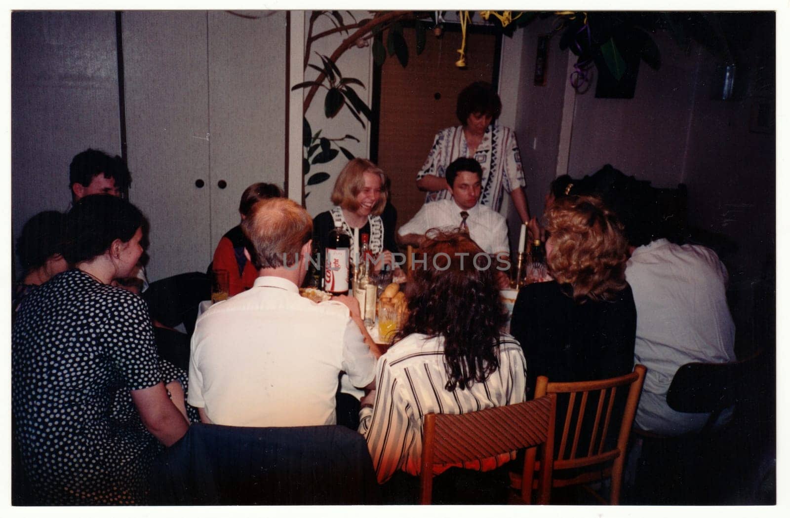 Retro photo shows people at the home party. Vintage color photography. Circa 1990. by roman_nerud