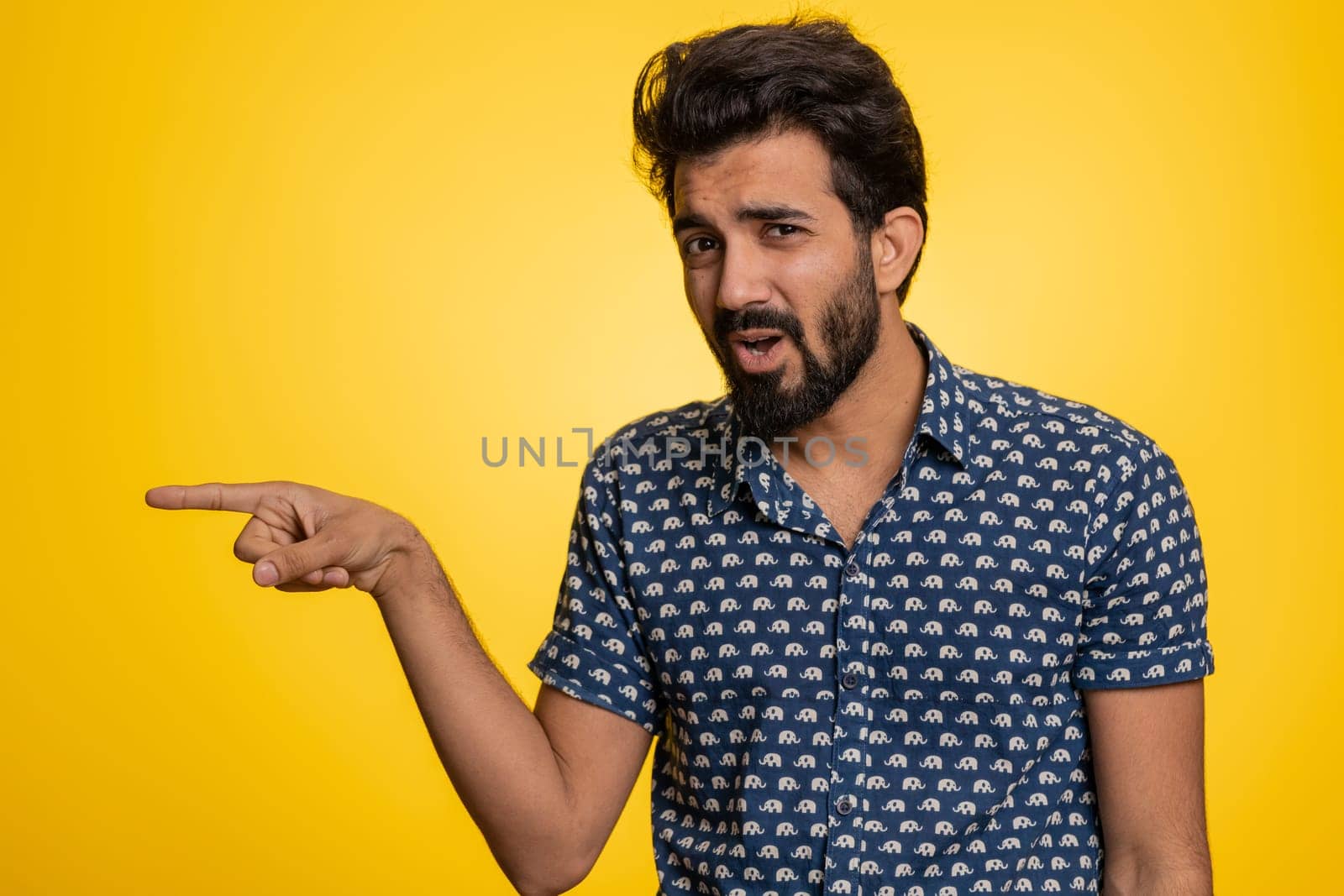 Get out of here. You are fired. Young irritated indian man pointing finger away asking to leave him alone, strict boss firing, conflict. Handsome hindu guy isolated on studio yellow background indoors