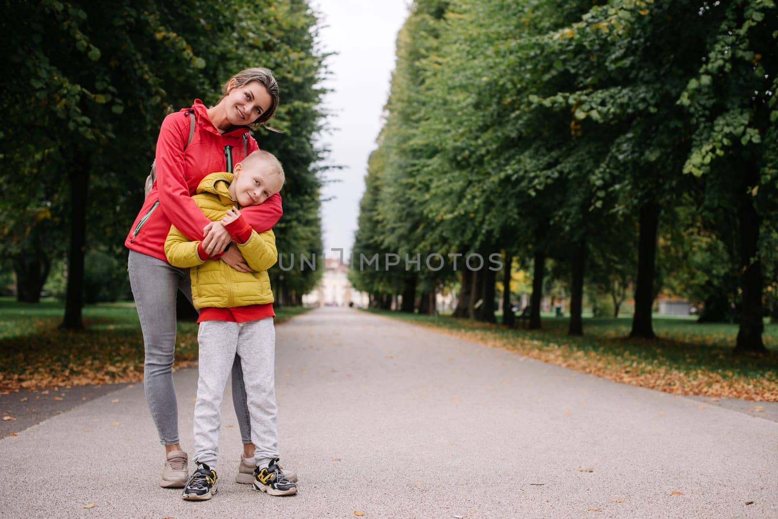 mother and son stand hugging in the park in the fall. happy mother playing with her son in the park. Mother hugs her son while standing in the forest in autumn.