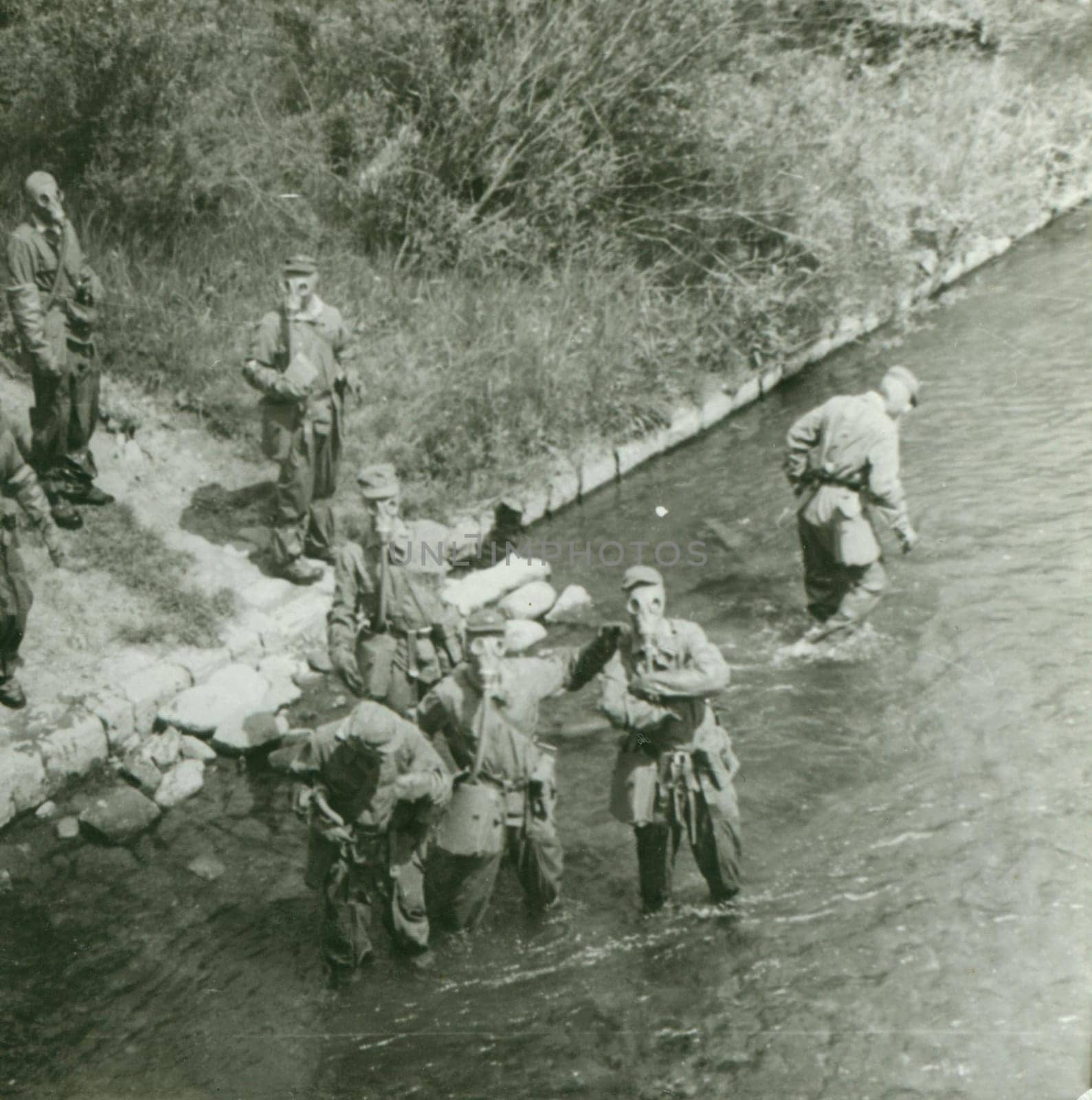 THE CZECHOSLOVAK SOCIALIST REPUBLIC - CIRCA 1970s: Retro photo shows young men - soldiers during army drill. Soldiers with gas masks on heads. Vintage photography. Circa 1970.