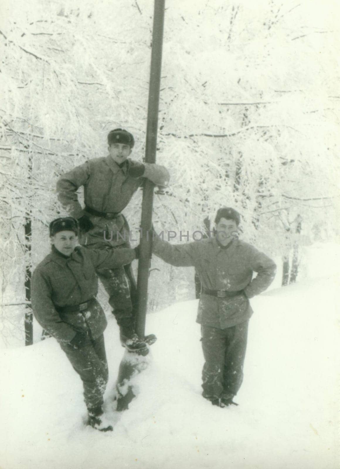 Retro photo shows young men - soldiers during winter time. Soldiers pose outdoors - snowy weather. Vintage photography. Circa 1970. by roman_nerud