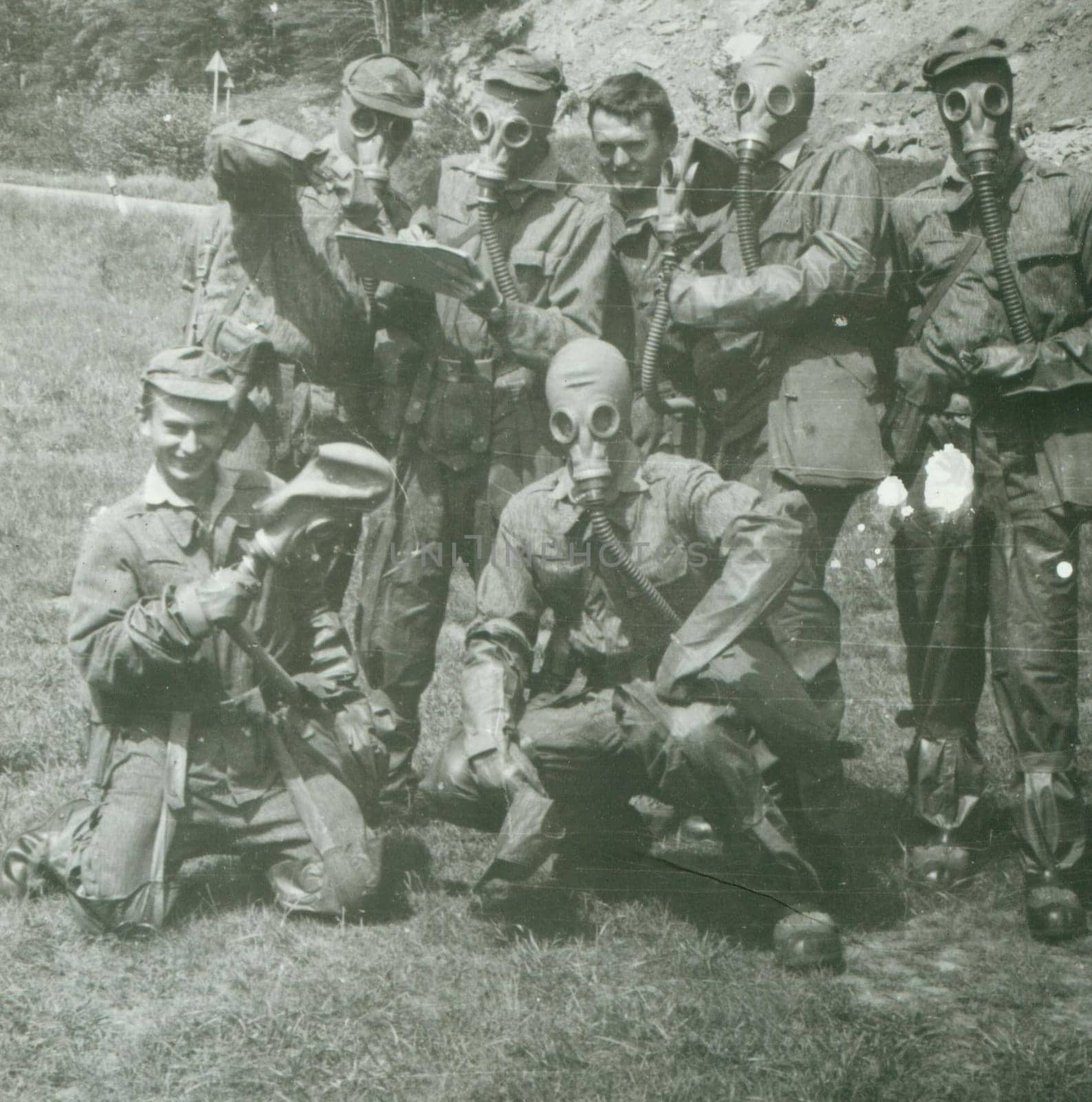 Retro photo shows young men - soldiers during army drill. Soldiers with gas masks on heads. Vintage photography. Circa 1970. by roman_nerud