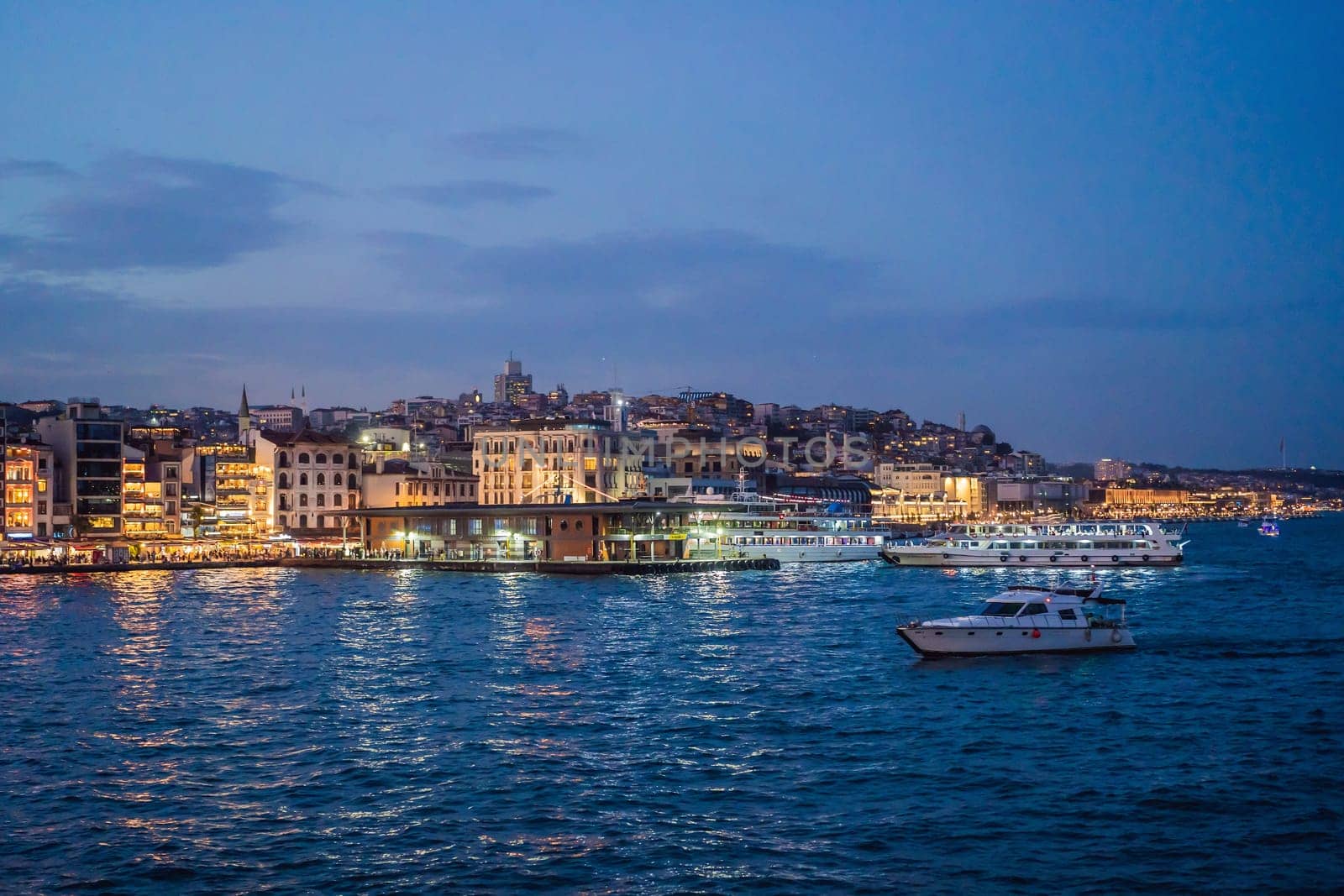 Istanbul at sunset, Turkey. Tourist boat sails on Golden Horn in summer. Beautiful sunny view of Istanbul waterfront with old mosque. Concept of travel, tourism and vacation in Istanbul and Turkey. Turkiye.