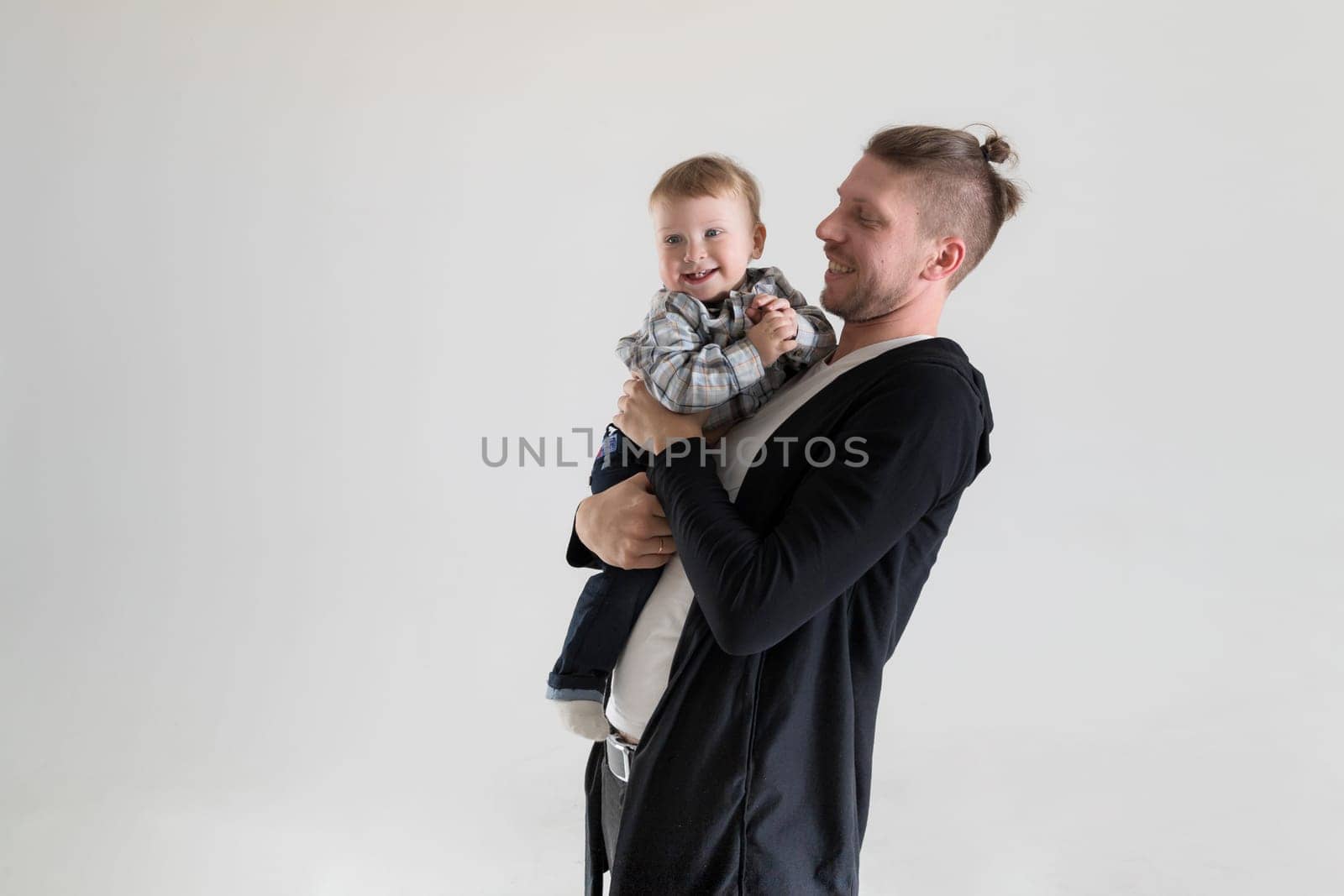 Young caucasian man holding smiling baby in her arms on a white background, copy space.