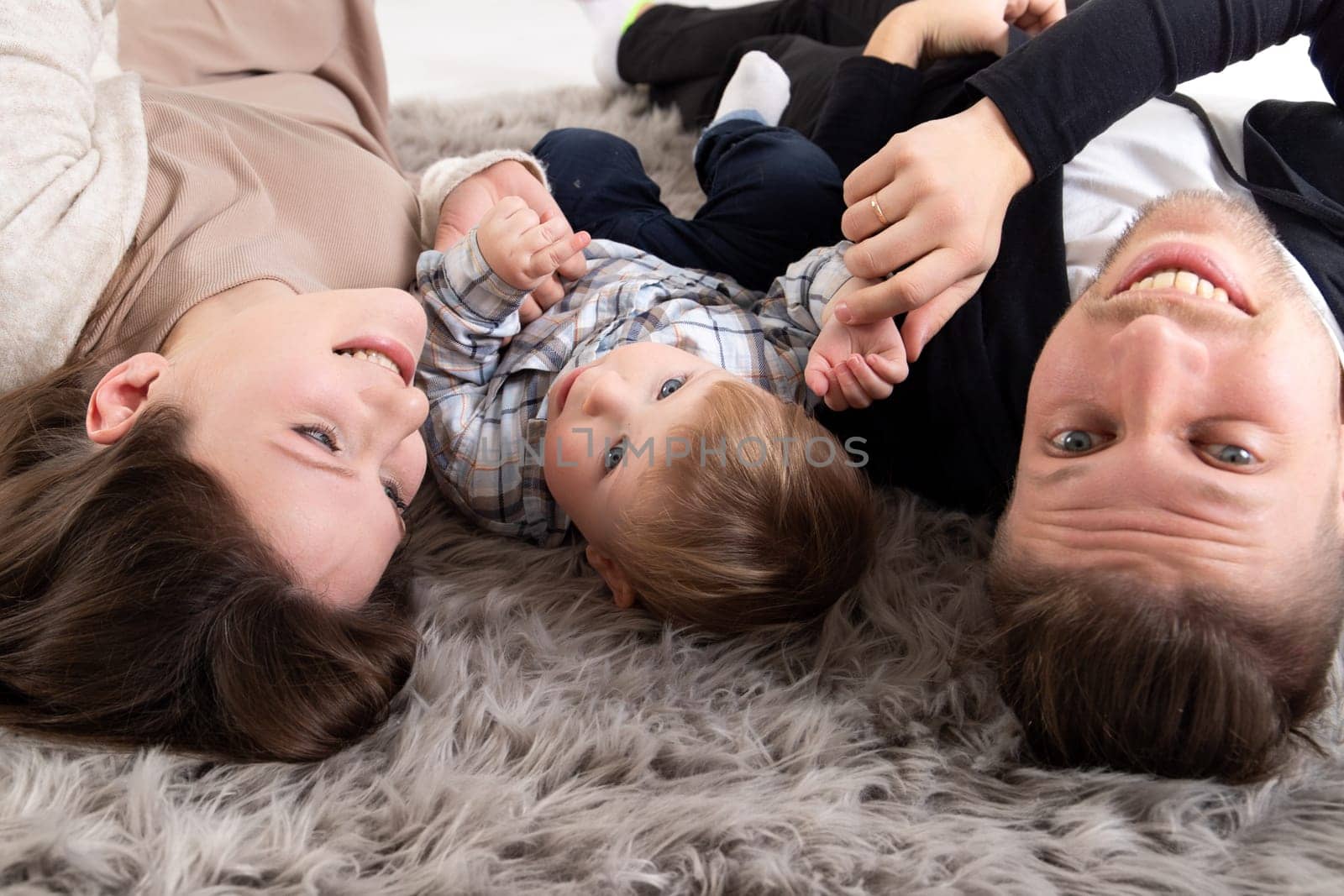 Young happy family have fun together lying on the floor. Close-up portrait by Rom4ek