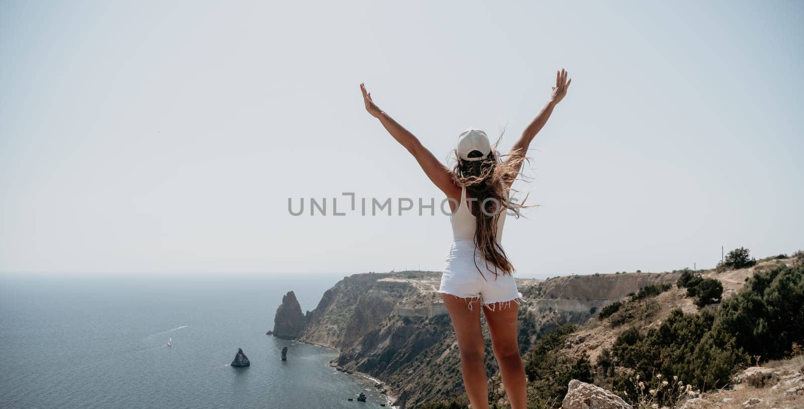 Woman summer travel sea. Happy tourist enjoy taking picture outdoors for memories. Woman traveler posing over sea bay surrounded by volcanic mountains, sharing travel adventure journey by panophotograph