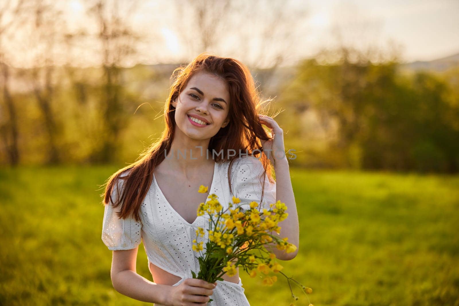 portrait of a happy woman with a bouquet of yellow flowers illuminated from the back by the setting sun by Vichizh