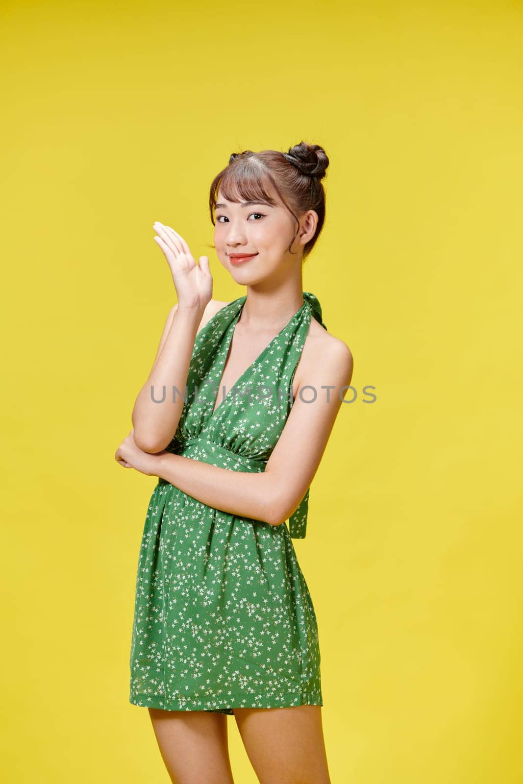 Sexy carefree woman posing near yellow wall in studio