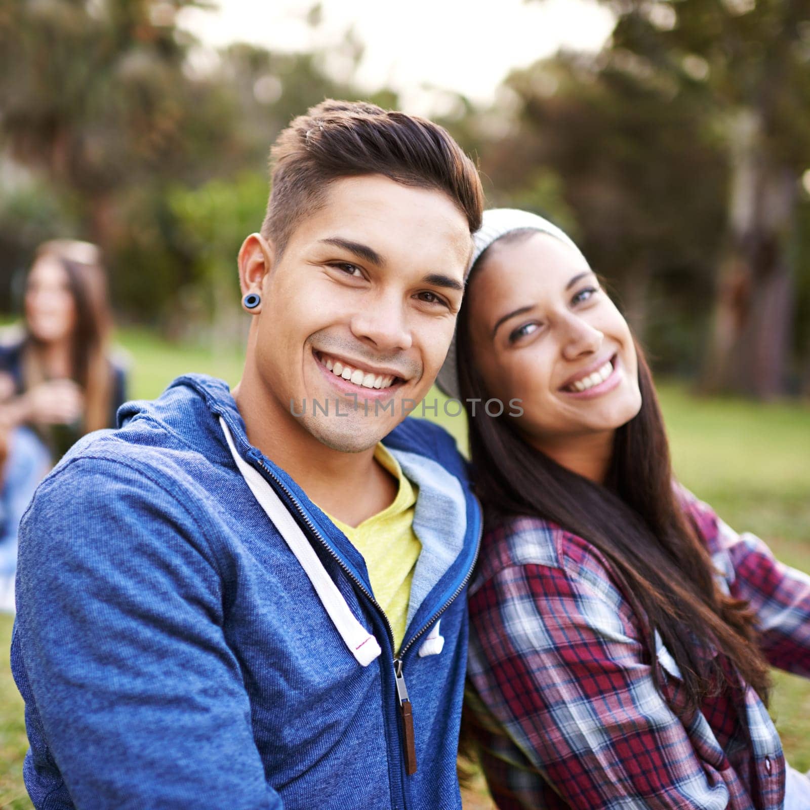 Sweethearts at the park. a young couple sitting together at the park. by YuriArcurs