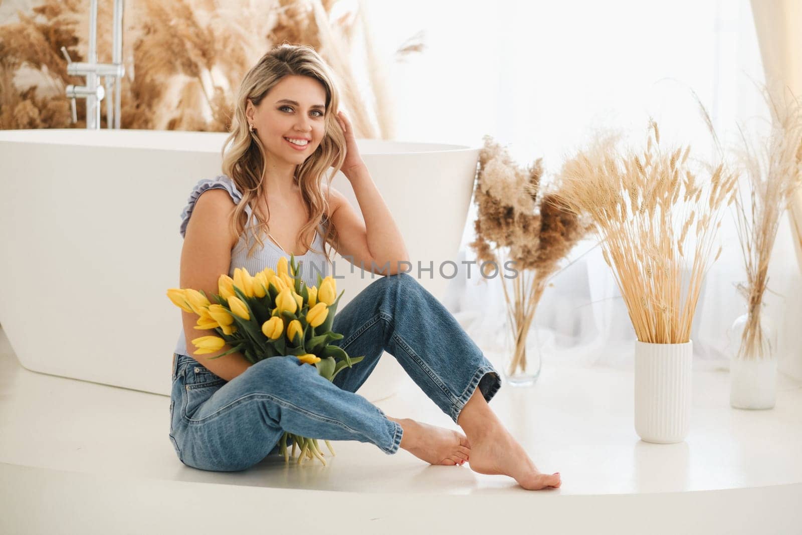 Cute smiling girl with a bouquet of yellow tulips in the interior.