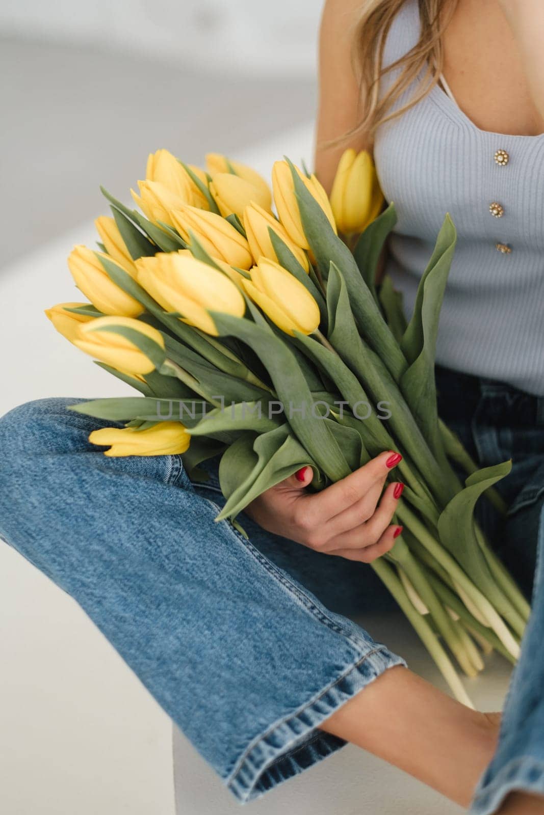 Cute smiling girl with a bouquet of yellow tulips in the interior.