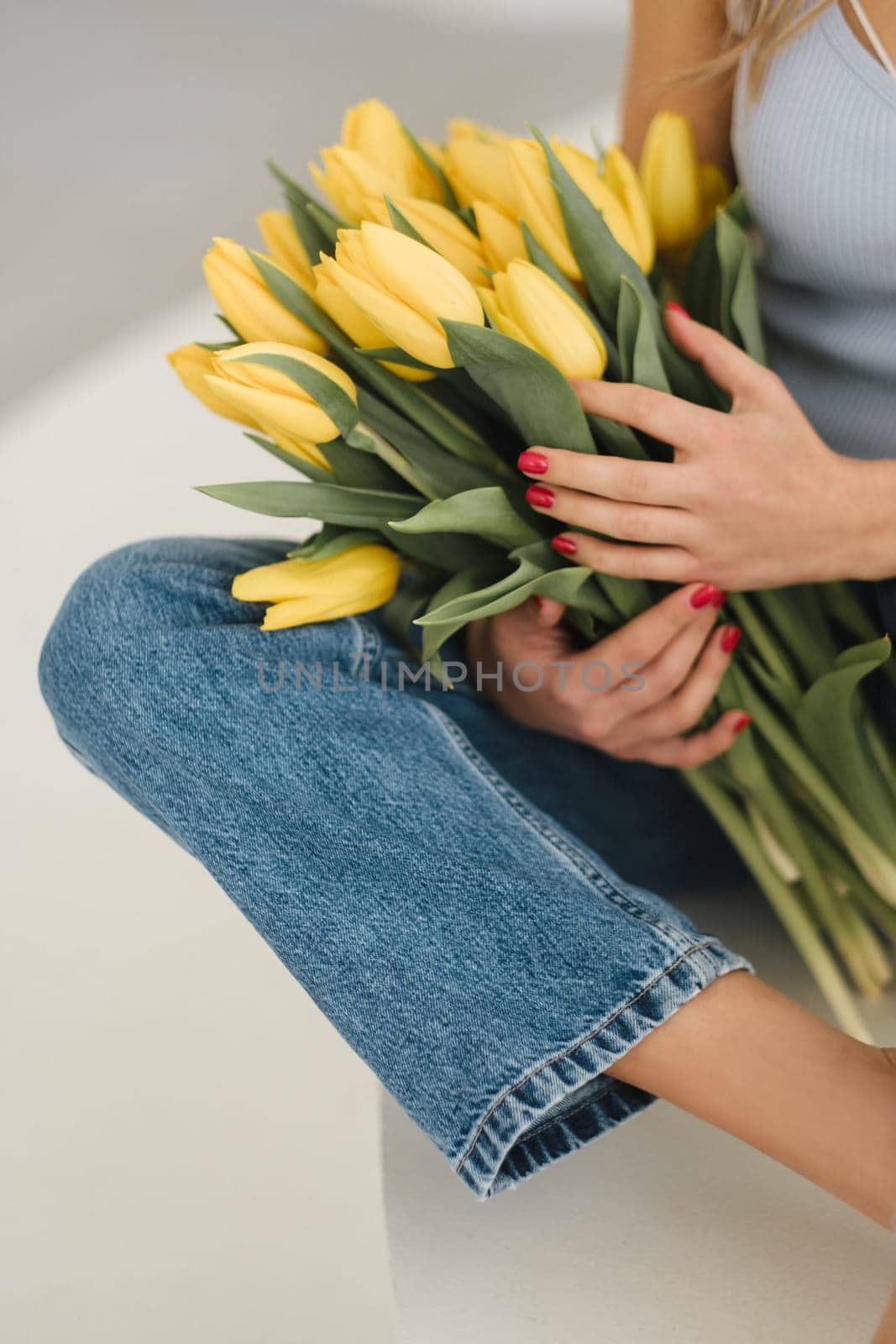 Cute smiling girl with a bouquet of yellow tulips in the interior.