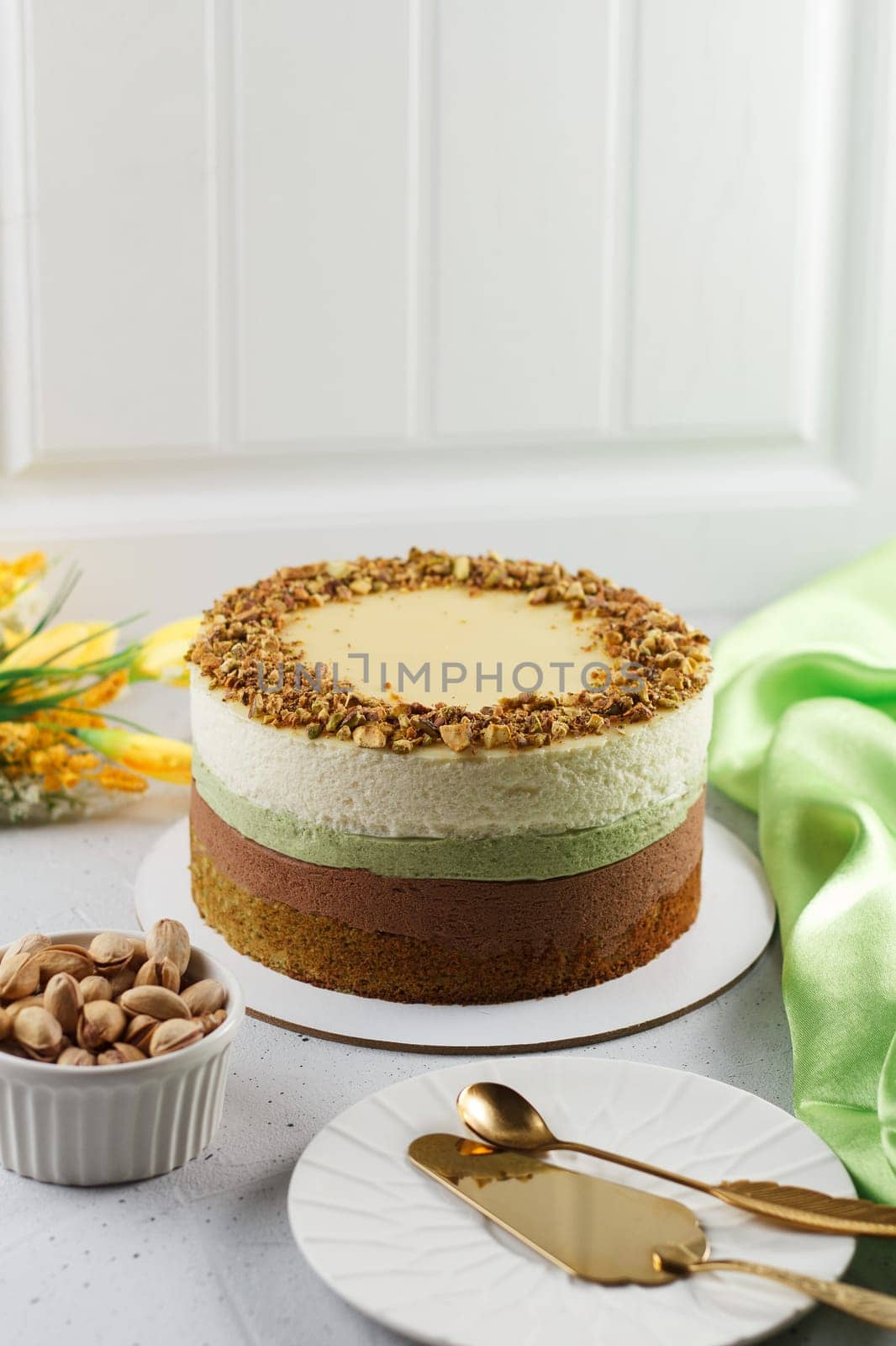 Pistachio cake on the table with cutlery, textile flowers. Ingredients: pistachio sponge cake, pistachio mousse, chocolate mousse and white chocolate mousse. by lara29