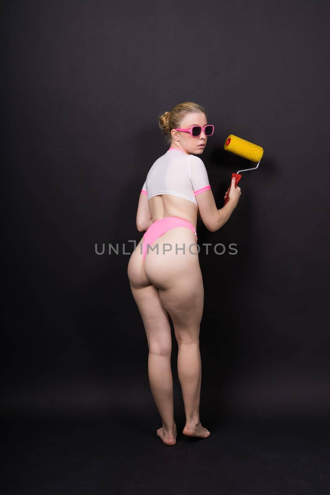 Beautiful topless blonde model holding a roller brush over one of her breasts by Zelenin