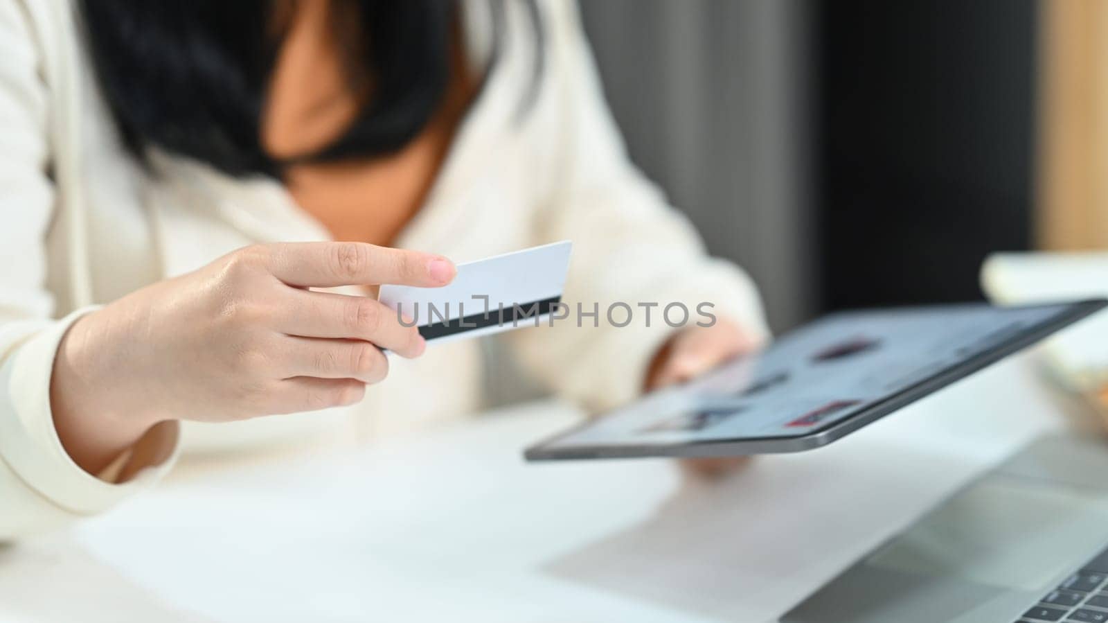 Woman hand holding credit card and using digital tablet, making orders via internet or transaction on bank application.