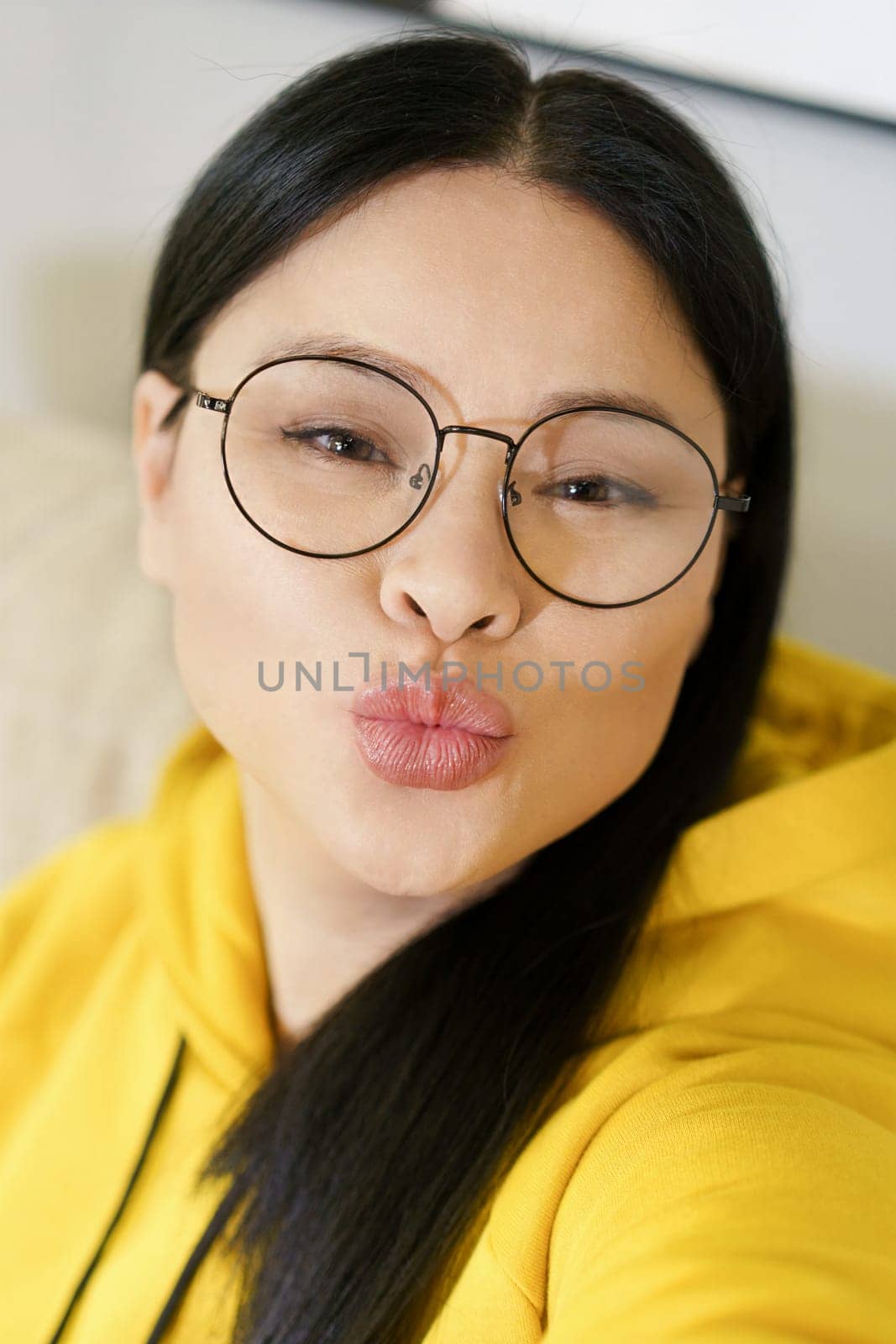 Young pretty woman takes selfies on her smartphone and applies filters and portrait processing applications. Use of technology and social media to capture and enhance self-portraits. by LipikStockMedia