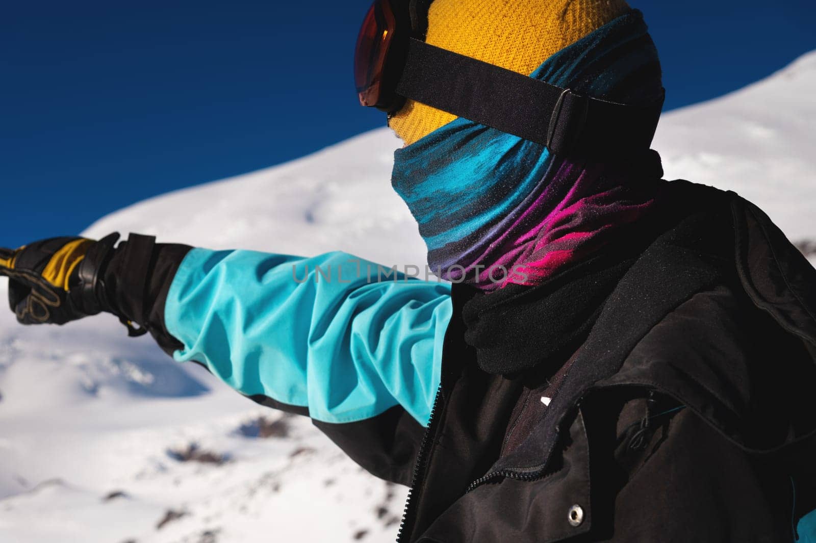 Side view of a tourist pointing with his hand in the right direction. Young man looking for direction in snowy mountains, portrait.